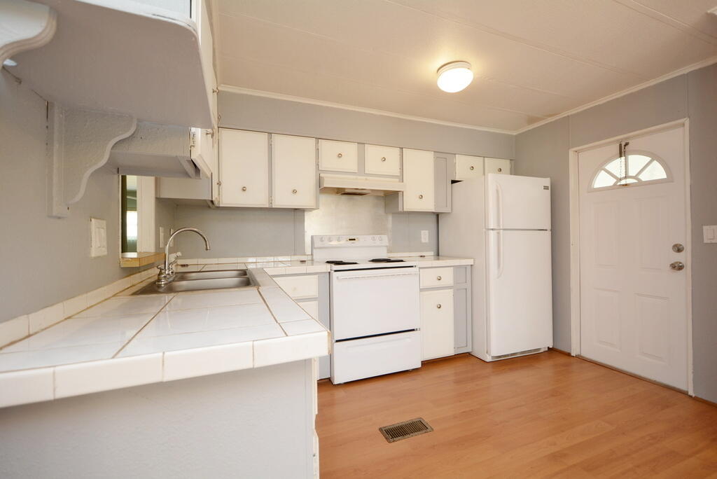 623 Periwinkle Circle Barefoot Bay, FL 32976 - Photo 15 of 37 a kitchen with a refrigerator and white cabinets