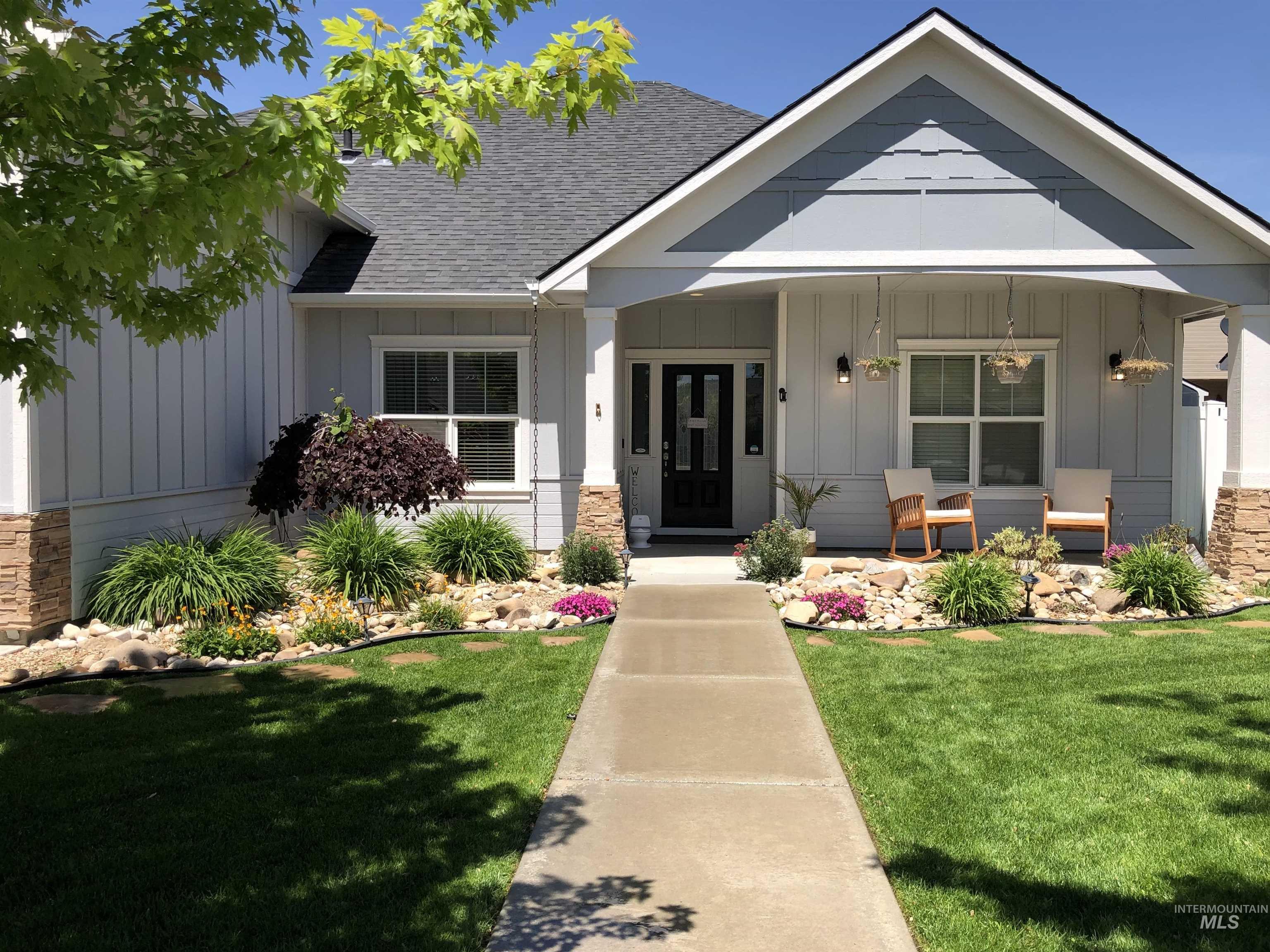 View of front facade featuring board and batten siding, a porch, a front lawn, a shingled roof, and stone siding