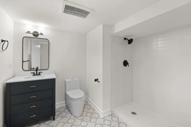 a bathroom with a toilet a sink a mirror and shower