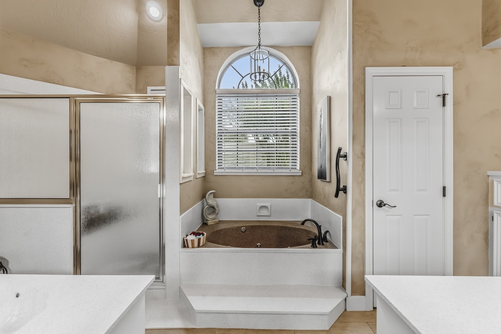 6047 Spring Creek Lane Spring, TX 77379 - Photo 11 of 50 The ensuite bath pairs classic proportions with a warm, neutral palette that feels quietly refined rather than overstated. A soaking tub positioned beneath the arched window and a separate glass enclosed shower create a layout designed for both comfort and function.