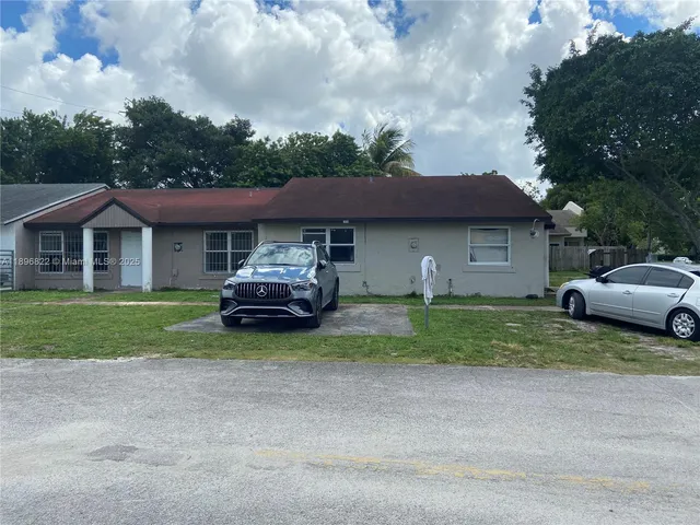 a front view of a house with a garden and trees