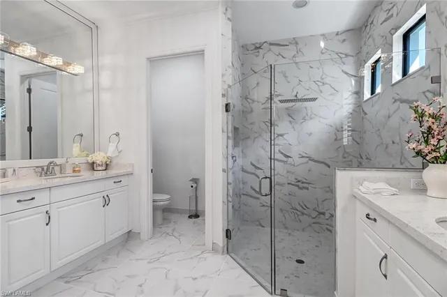 a bathroom with a granite countertop sink a toilet and shower