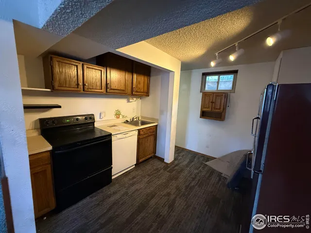 a kitchen with granite countertop a refrigerator and wooden floor