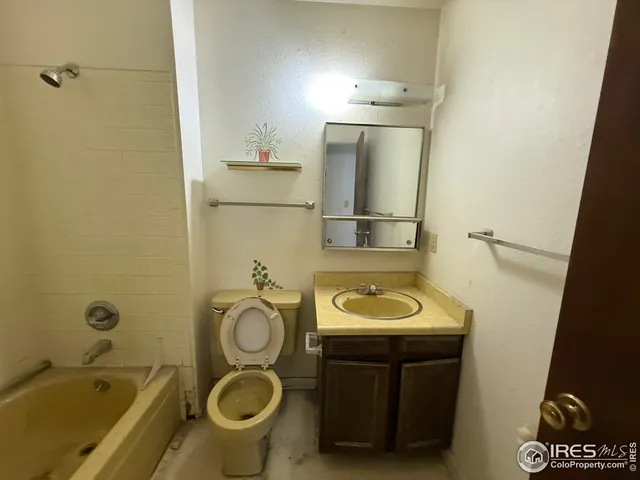 a bathroom with a granite countertop toilet sink and mirror