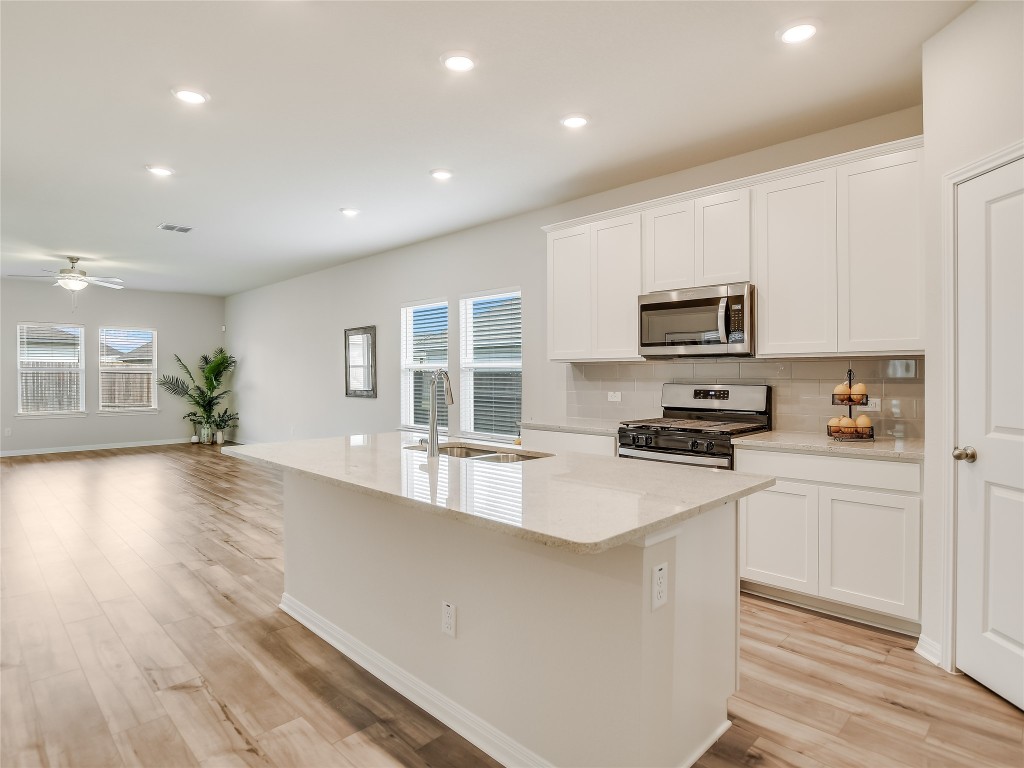 2818 Rustic Hills Drive Round Rock, TX 78665 - Photo 4 of 26 a large kitchen with stainless steel appliances a large counter top a stove a refrigerator cabinets and a wooden floor
