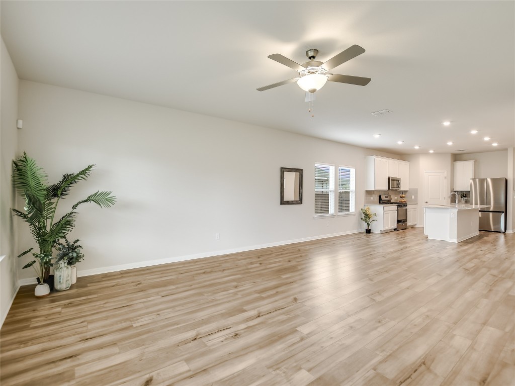 2818 Rustic Hills Drive Round Rock, TX 78665 - Photo 6 of 26 a view of an empty room with wooden floor and a ceiling fan