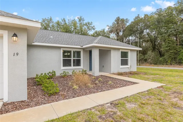 a view of an empty room with a kitchen and a ceiling fan