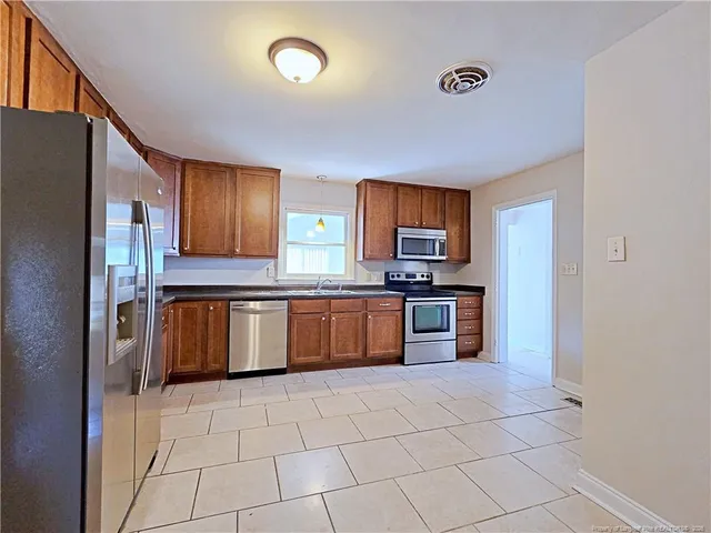 a large kitchen with granite countertop a stove a sink dishwasher a refrigerator and a stove top oven with wooden floor