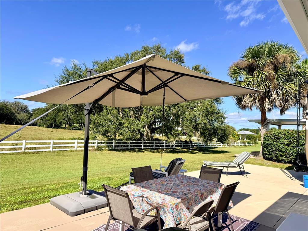 9594 Southeast 47th Way Webster, FL 33597 - Photo 16 of 50 a view of a swimming pool with a table and chairs under an umbrella