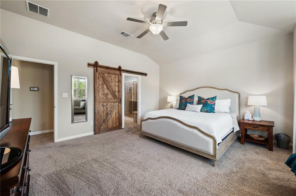 109 Hunt's Link Road Dripping Springs, TX 78620 - Photo 13 of 27 a bedroom with a large bed and a chandelier