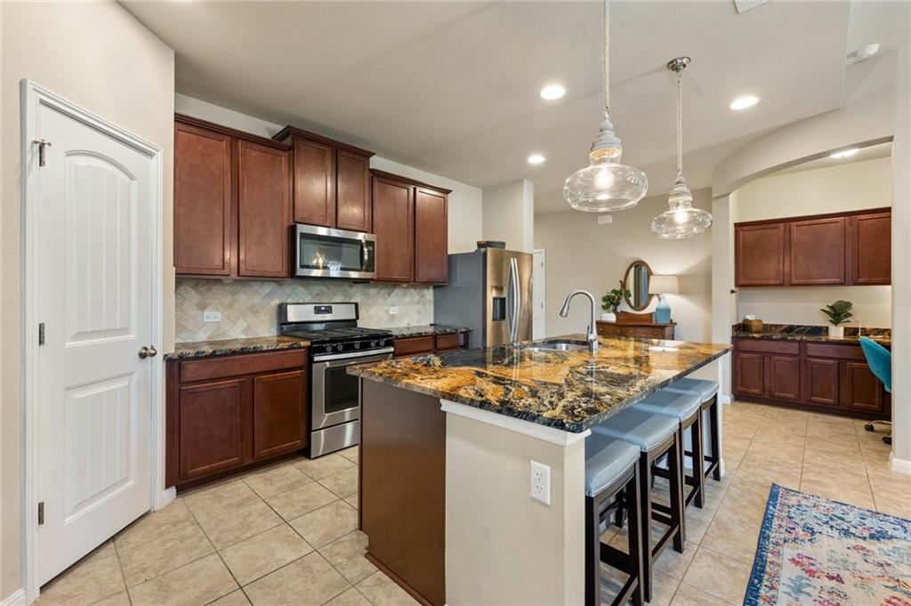 109 Hunt's Link Road Dripping Springs, TX 78620 - Photo 2 of 27 a kitchen with stainless steel appliances granite countertop a stove top oven a sink dishwasher a dining table and chairs with wooden floor