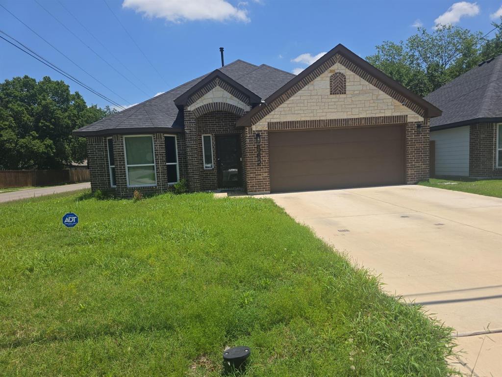 View of front of property with brick siding, an attached garage, driveway, and a front yard