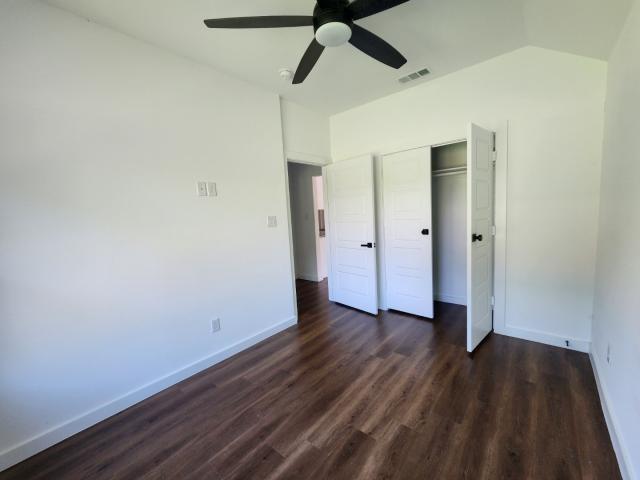 562 Jonelle Avenue Dallas, TX 75217 - Photo 12 of 20 Unfurnished bedroom featuring dark wood finished floors, lofted ceiling, a ceiling fan, and a closet