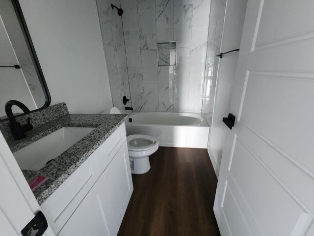 562 Jonelle Avenue Dallas, TX 75217 - Photo 13 of 20 Full bathroom featuring vanity, washtub / shower combination, and dark wood-style flooring