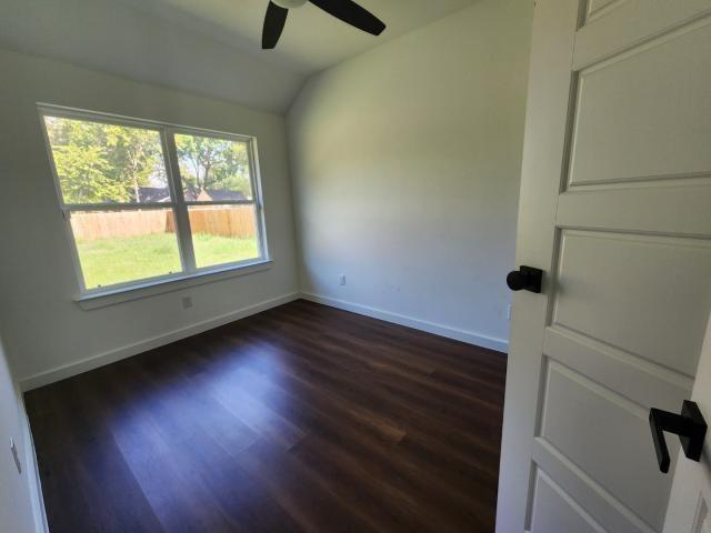 562 Jonelle Avenue Dallas, TX 75217 - Photo 15 of 20 Spare room with dark wood-style flooring, lofted ceiling, and ceiling fan