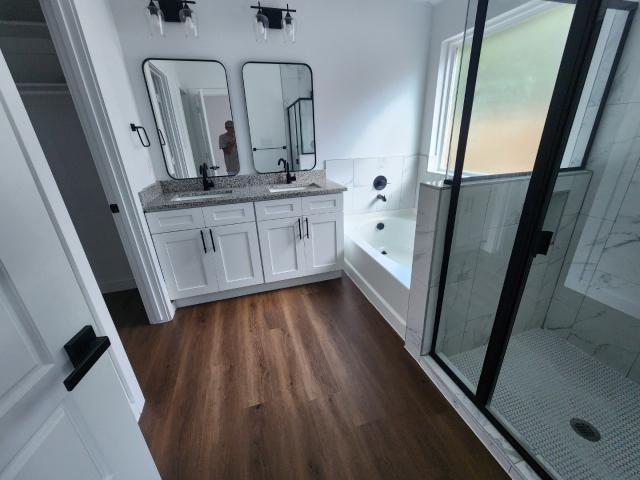 562 Jonelle Avenue Dallas, TX 75217 - Photo 16 of 20 Bathroom featuring double vanity, a marble finish shower, a bath, and dark wood-type flooring