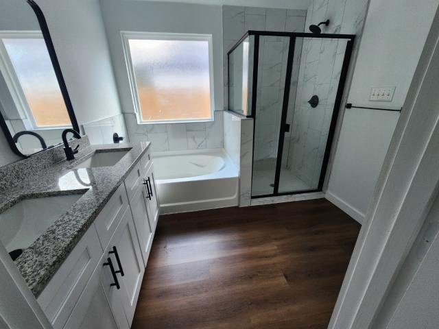 562 Jonelle Avenue Dallas, TX 75217 - Photo 17 of 20 Bathroom with double vanity, a marble finish shower, dark wood-style flooring, and a garden tub