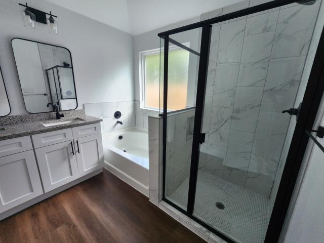 562 Jonelle Avenue Dallas, TX 75217 - Photo 18 of 20 Full bath featuring dark wood-type flooring, vanity, a marble finish shower, and a garden tub