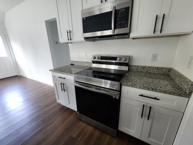 562 Jonelle Avenue Dallas, TX 75217 - Photo 7 of 20 Kitchen with stainless steel appliances, dark wood finished floors, white cabinets, and dark stone countertops
