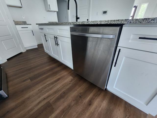 562 Jonelle Avenue Dallas, TX 75217 - Photo 8 of 20 Kitchen with stainless steel dishwasher, dark wood-style floors, light stone counters, and white cabinetry