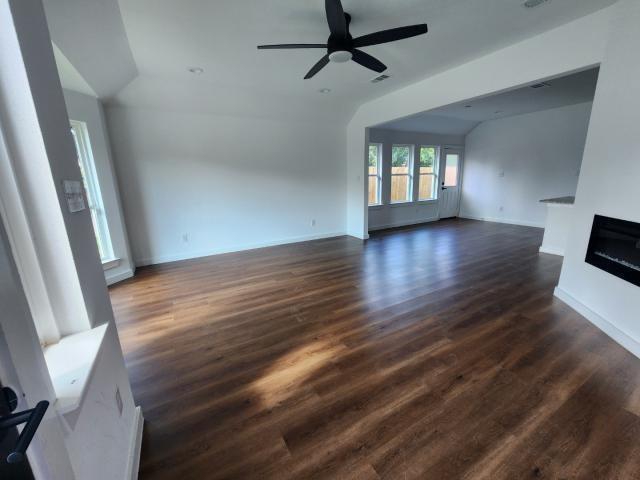 562 Jonelle Avenue Dallas, TX 75217 - Photo 10 of 20 Unfurnished living room with dark wood-style floors, ceiling fan, a glass covered fireplace, and vaulted ceiling