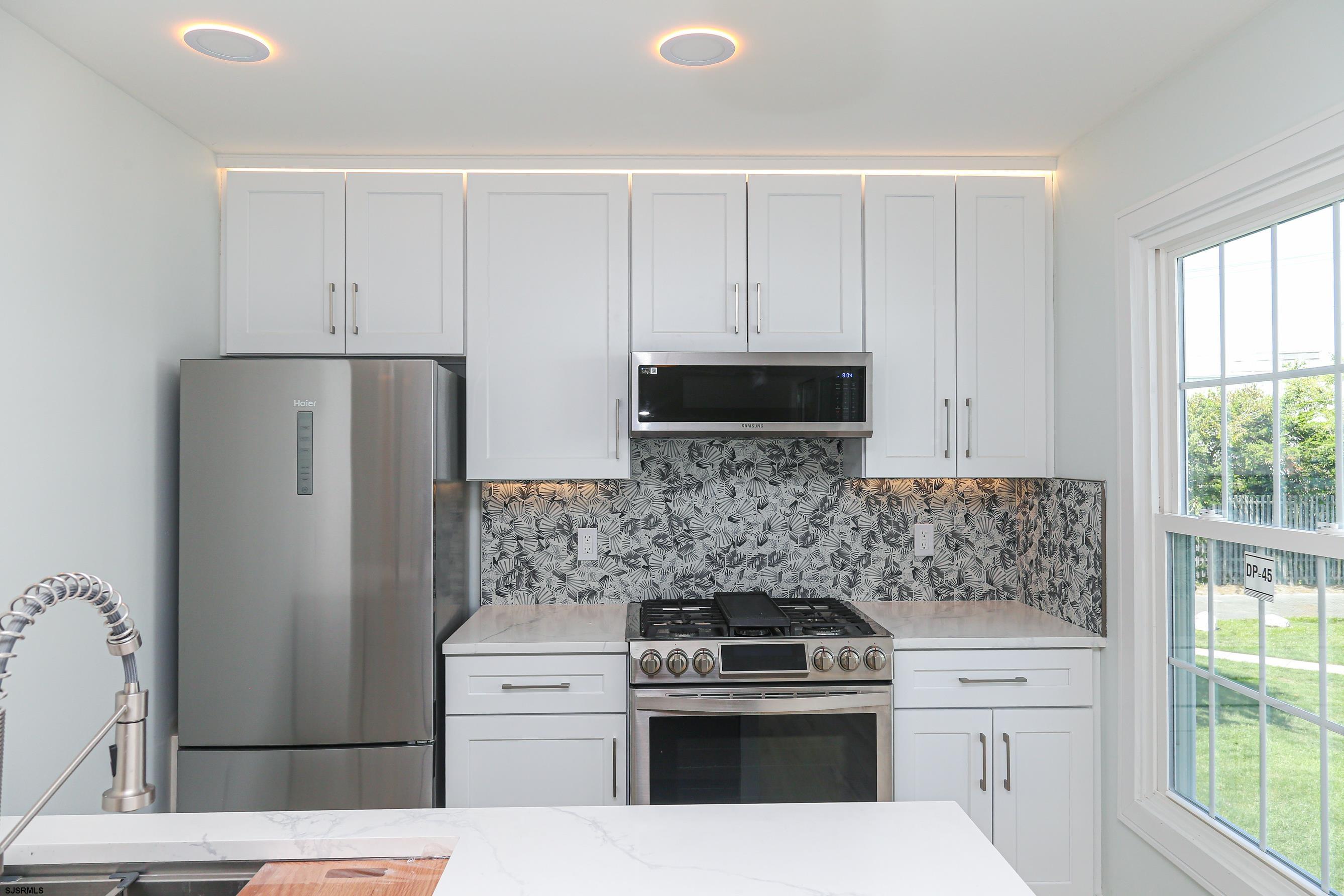 169 40th Street South, Unit 38 Brigantine, NJ 08203 - Photo 14 of 79 a kitchen with white cabinets and stainless steel appliances