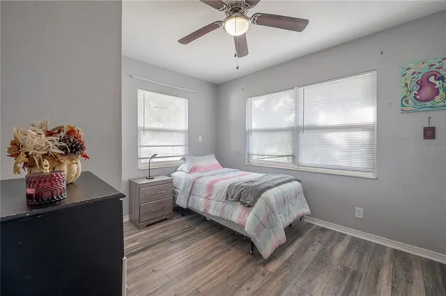a bedroom with a bed potted plant on dresser and a window