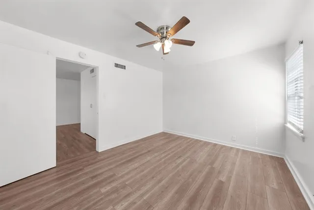 an empty room with wooden floor and a ceiling fan