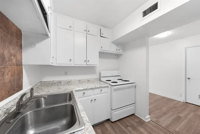 a kitchen with white cabinets sink and appliances