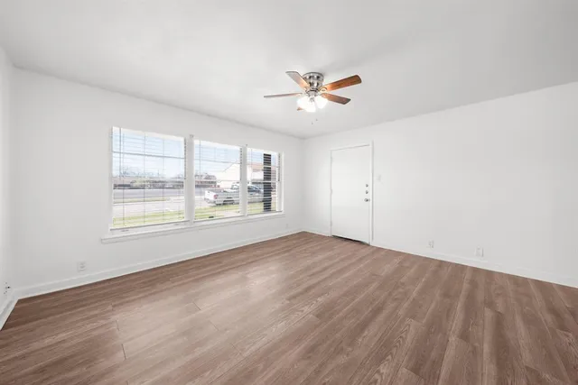 a view of an empty room with a window and wooden floor
