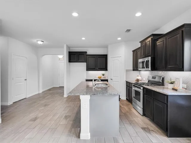 a kitchen with stainless steel appliances granite countertop a sink stove and refrigerator