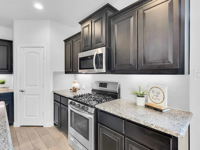 a kitchen with stainless steel appliances granite countertop a stove a microwave and cabinets