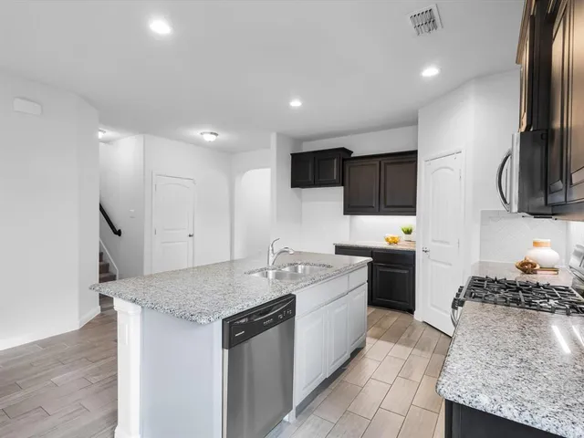 a kitchen with granite countertop a sink stainless steel appliances and cabinets
