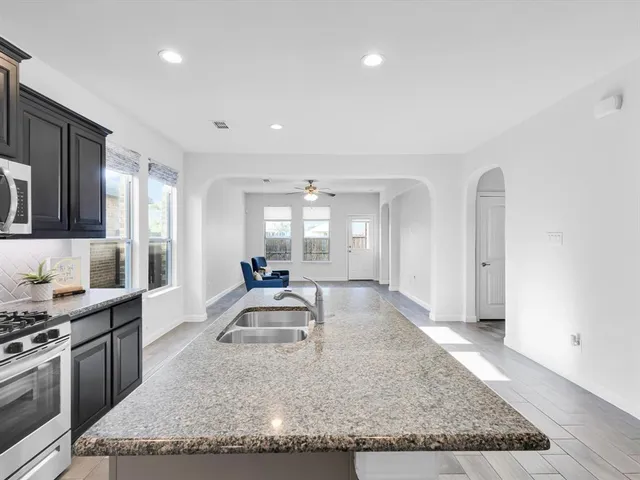 a large kitchen with granite countertop a sink and cabinets