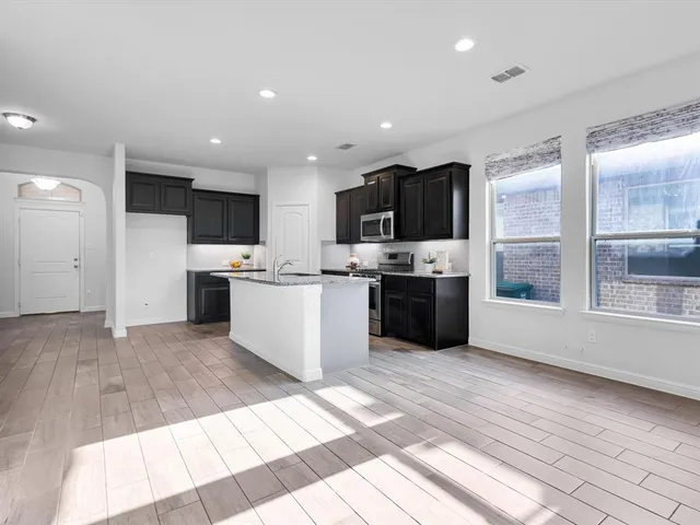 a large kitchen with a sink stainless steel appliances and cabinets