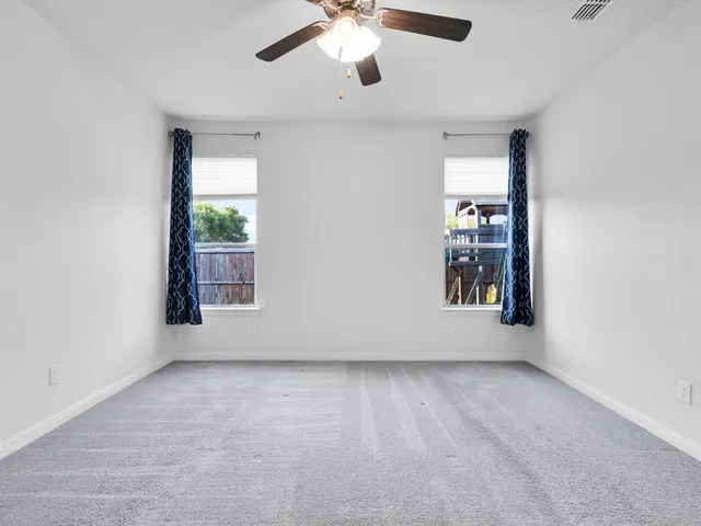 an empty room with windows and chandelier fan