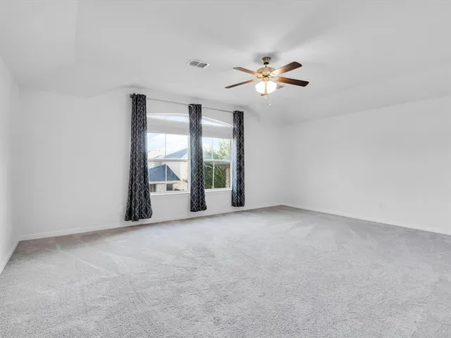 a view of an empty room with chandelier fan and a window