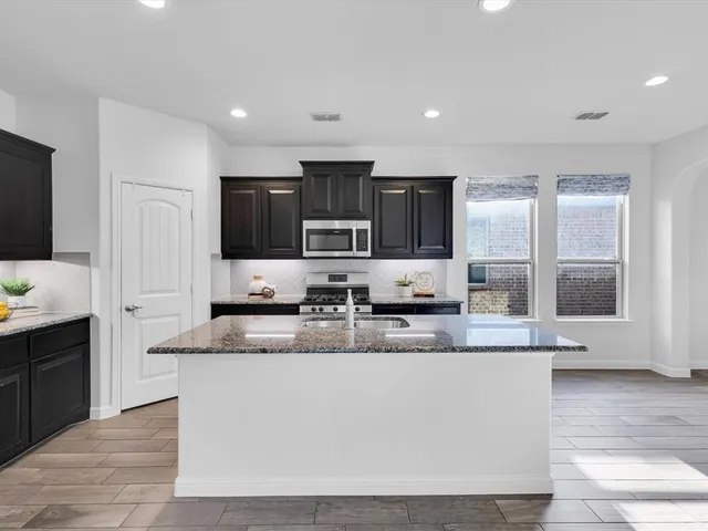 a large kitchen with granite countertop a sink a counter top space appliances and cabinets