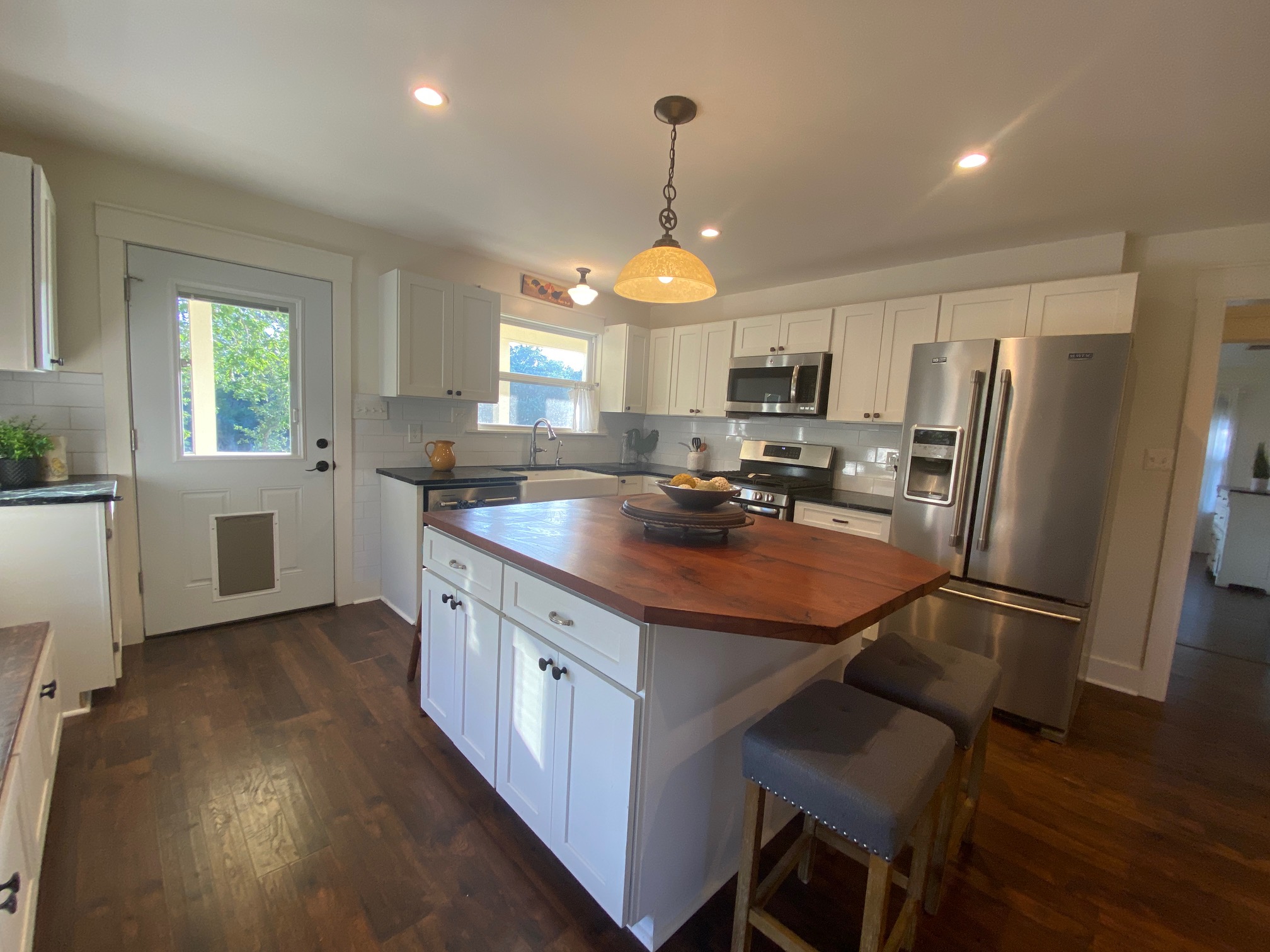 306 Plainview Road Wimberley, TX 78676 - Photo 7 of 29 A well-lit kitchen with rich hardwood floors and a spacious island featuring a warm wood countertop.