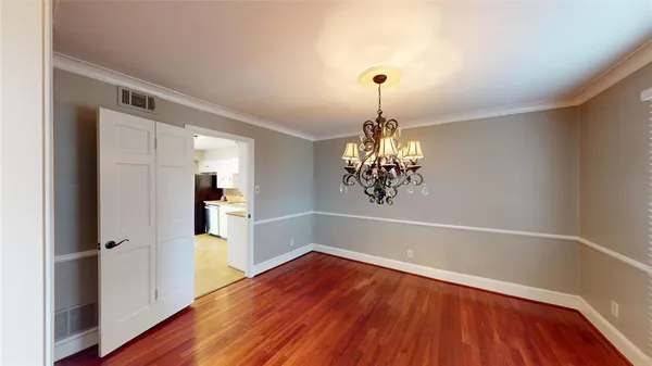 a view of a hallway with wooden floor and chandelier