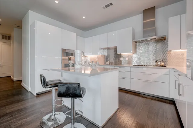 a kitchen with stainless steel appliances granite countertop a stove a sink dishwasher and white cabinets with wooden floor