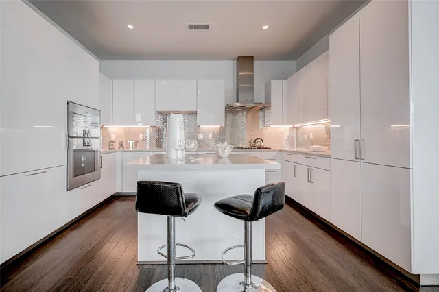 a kitchen with stainless steel appliances kitchen island granite countertop a refrigerator a stove a sink dishwasher and white cabinets with wooden floor