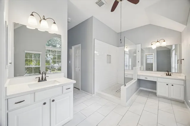 a bathroom with a double vanity sink mirror and bathtub