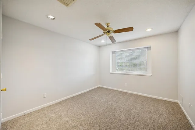 an empty room with a window and a ceiling fan