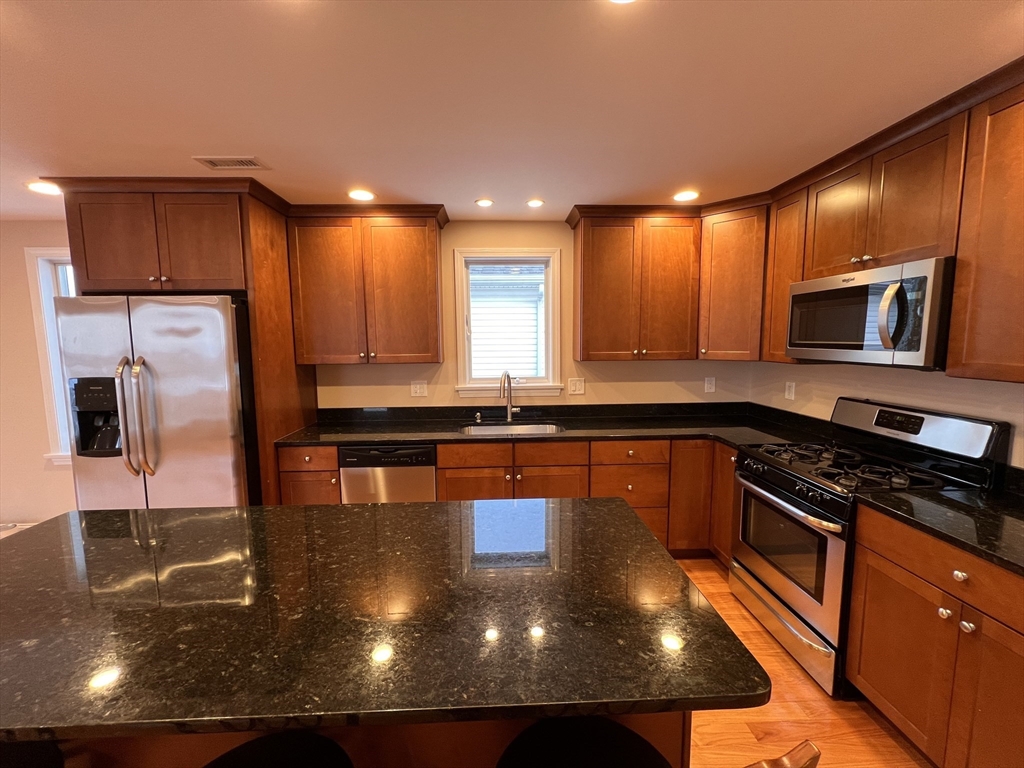a kitchen with stainless steel appliances granite countertop a sink a stove counter space and a refrigerator
