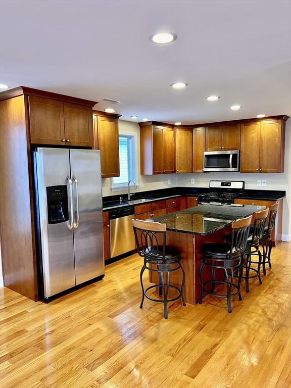 31 Rand Street, Unit 2 Revere, MA 02151 - Photo 2 of 15 a kitchen with stainless steel appliances kitchen island granite countertop a table and chairs in it