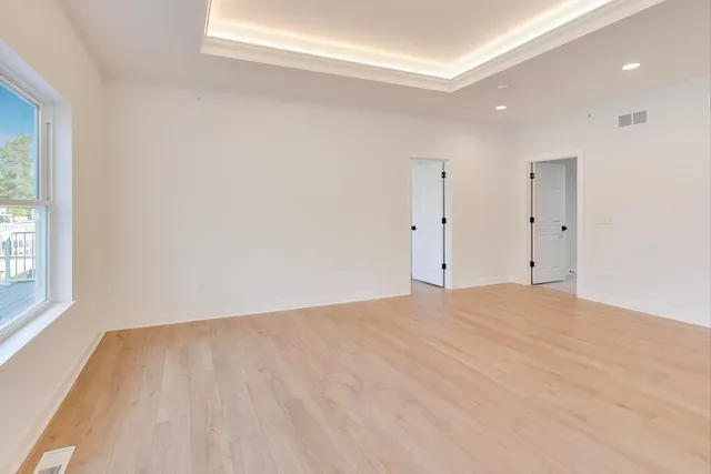 a view of empty room with wooden floor and fan