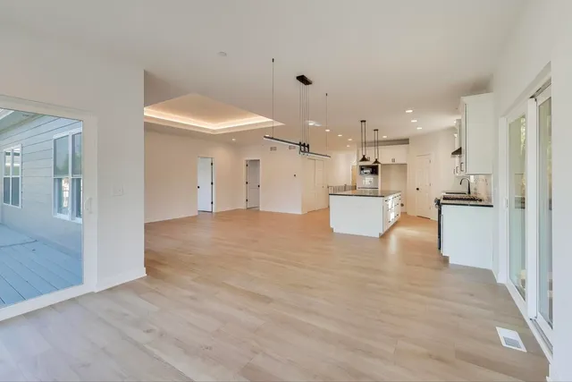a view of a kitchen with kitchen island a sink wooden floor and a refrigerator