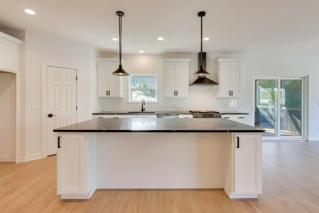 a kitchen with stainless steel appliances granite countertop a sink a window and chairs