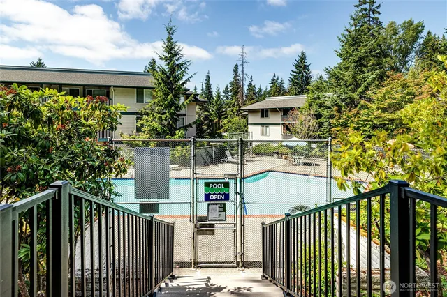a sign that is sitting in front of a house with large trees